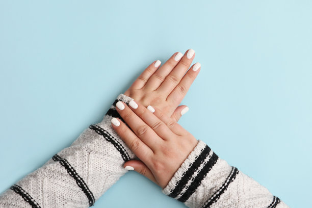 节日的女人用白色修指甲。舒适的气氛。壮观的指甲与白色装饰。柔和的颜色,简约的概念。圣诞节修指甲的点子，大横幅。图片下载