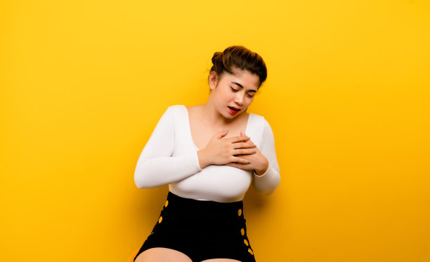 亚洲妇女有胸痛健康问题和心痛的黄色背景。图片下载
