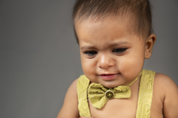 灰色背景下可爱的小女孩哭泣的特写。图片下载