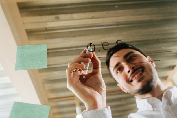 一个年轻的经理在一个清晰的塑料板上写字图片下载