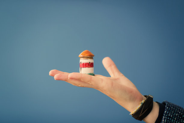 陶瓷灯塔在女人的手特写在蓝色的背景。教练导向目标的指导概念图片下载