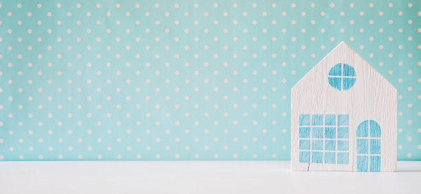 蓝色背景上的小木制玩具房子。简约的背景和复制空间图片下载
