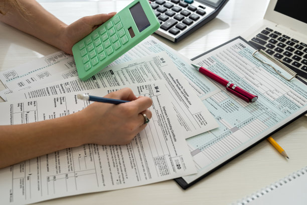 女人在办公室用笔记本电脑和计算器填写美国税务表格图片下载