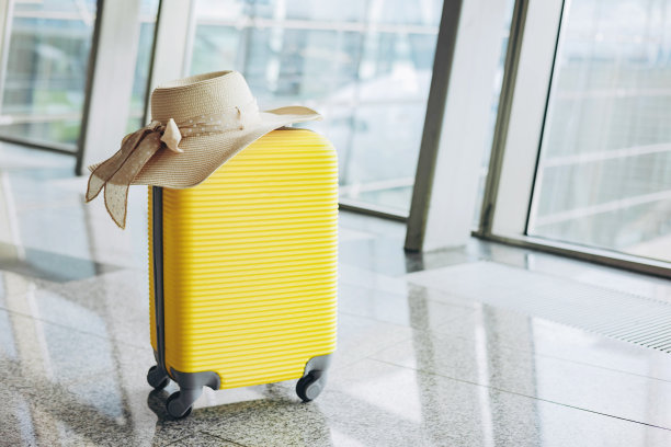 飞机背景下的候机室里，黄色的手提箱和草帽。旅游和暑假的概念。在机场候机室的明亮的手提箱。图片下载