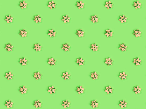 绿色背景上手工制作的木质雪花的美丽图案。图片下载