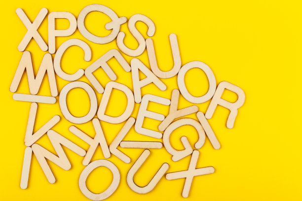 木制字母在黄色的纸背景上。图片下载