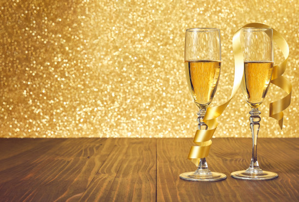 棕色木桌上放着两杯香槟，上面有金色的圣诞球图片下载