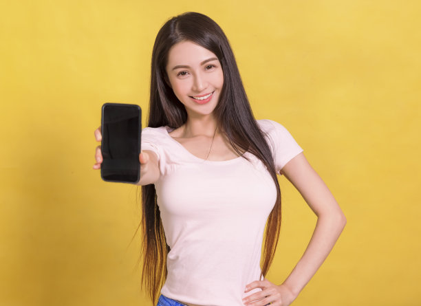 美丽的亚洲年轻女子显示空白屏幕的手机。图片下载