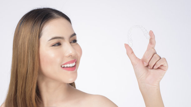 年轻微笑的女人手持无牙矫正器在工作室，牙科保健和正畸的概念图片下载