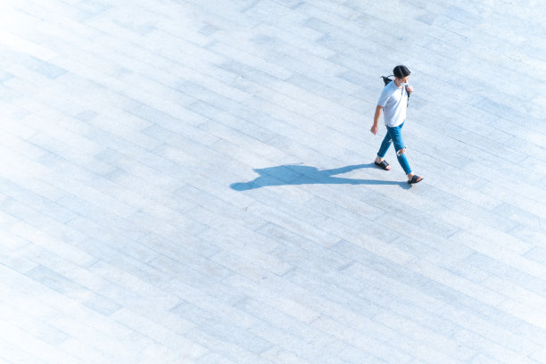 顶鸟瞰图，戴着口罩的人走过地面黑色剪影的行人混凝土，社会新常态生活的概念，预防covid - 19大流行和空气污染。图片下载