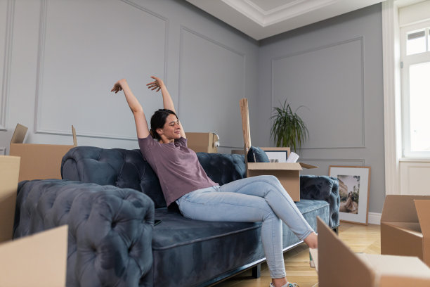 微笑的女人在新家里打开行李后感到疲惫。图片下载