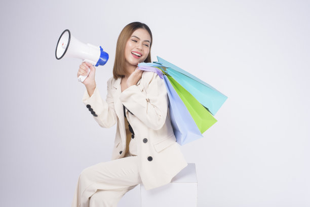 年轻漂亮的女人在西装拿着五颜六色的购物袋在白色的背景工作室图片下载
