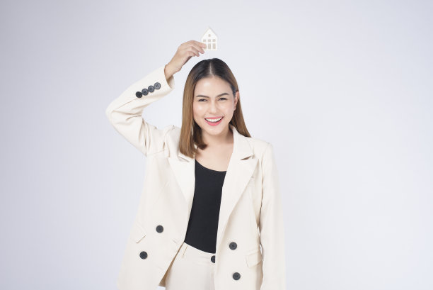 年轻漂亮的女人在西装手持小模型房子在白色背景的工作室图片下载