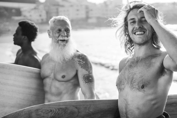 多代冲浪者在海滩上的乐趣-集中在正确的人的脸图片下载