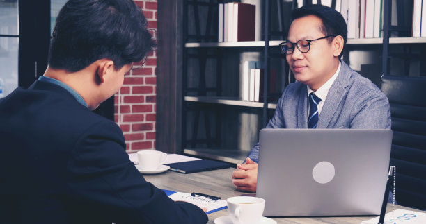 两名商人共同签署合同文件，启动业务协议，进行团队合作。近手的年轻人同事开会并购业务。合伙人在办公室签署文件。图片下载