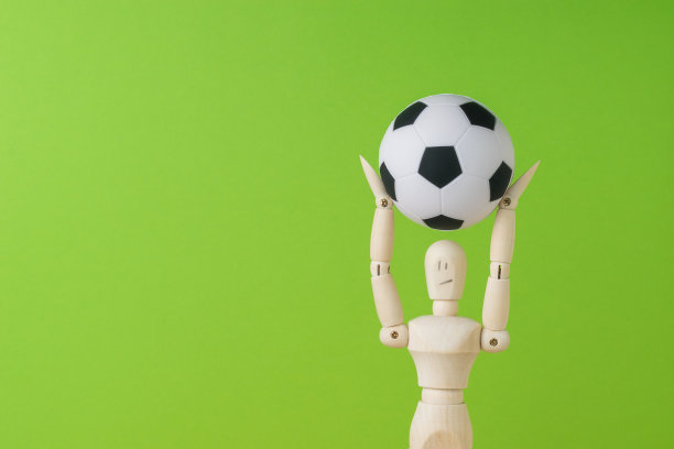绿色背景上一个木头人手里的足球。空间的文本。图片下载