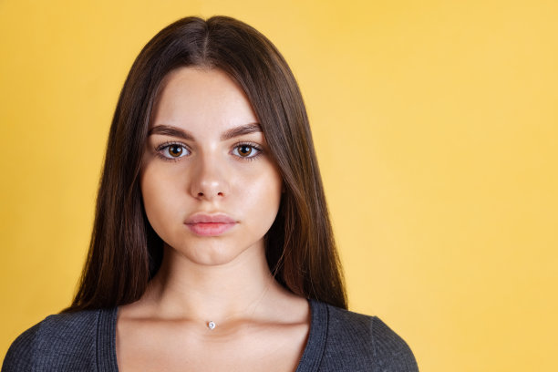 特写的年轻美丽的白人妇女看着相机孤立在黄色背景图片下载