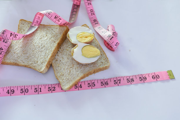 全麦面包、鸡蛋和卷尺，健康饮食理念，降低身体脂肪含量图片下载