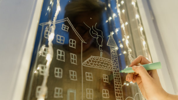 女性手画圣诞假期装饰在窗户玻璃上。图片下载