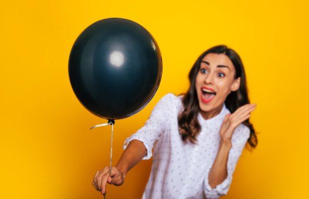 特写照片，美丽兴奋快乐的女人手里拿着一个黑色的氦气球，就像黑色星期五和购物日的象征图片下载