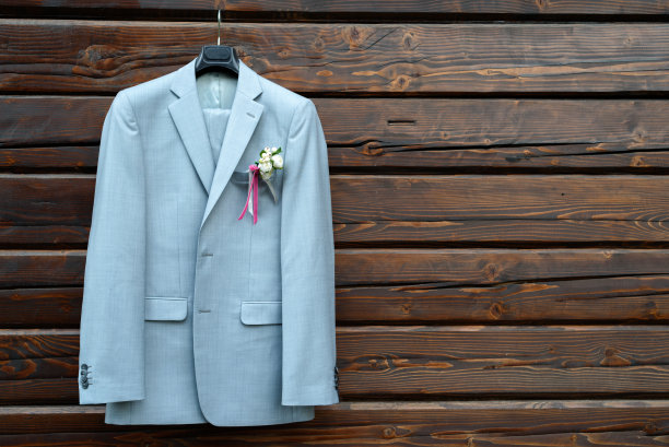 风格优雅的婚礼新郎西装挂在木制背景与复制空间的胸花。新郎婚礼饰品，自由空间图片下载