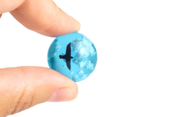 小玻璃球，上面有一个鸟的雕像，飞在云端图片下载