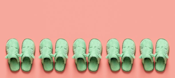 猫脸拖鞋在一排在橘色背景与复制空间。珊瑚色表面的青瓷绿色舒适家居拖鞋图案。有趣舒适的室内鞋概念。平的。图片下载