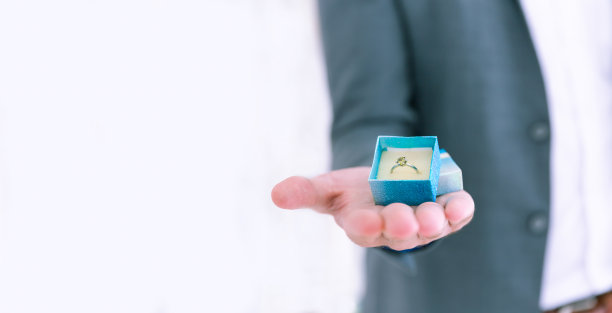 特写男子手持结婚银戒指在一个西装和礼盒，复制空间图片下载