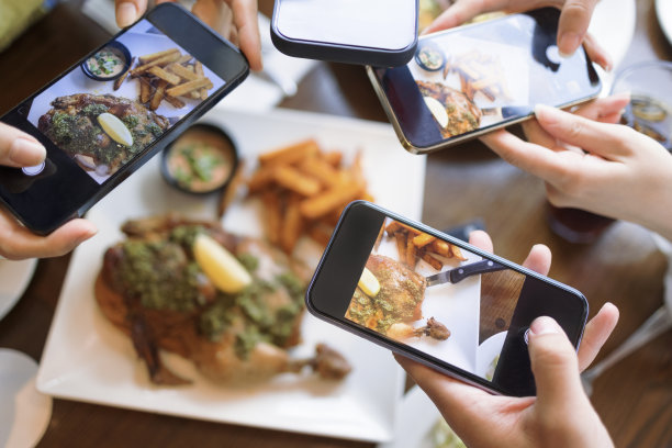 一群朋友在饭前用智能手机拍照。前视图。图片下载