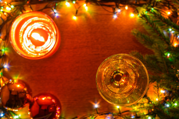 一盆气泡酒，一根蜡烛，两个闪亮的球在模糊的木制背景上。图片下载