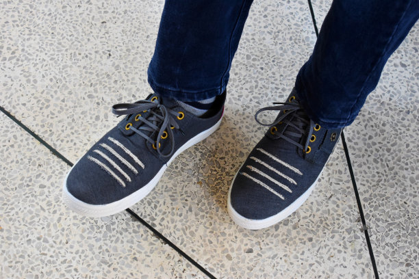 穿着蓝色牛仔裤和灰色鞋子的男人的腿图片下载