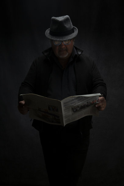 一名男子肖像在一盏灯下阅读报纸，这是一幅低调的肖像图片下载