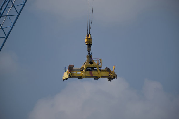 一种以蓝天为背景的悬挂在空中的工业起重机自动吊具图片下载