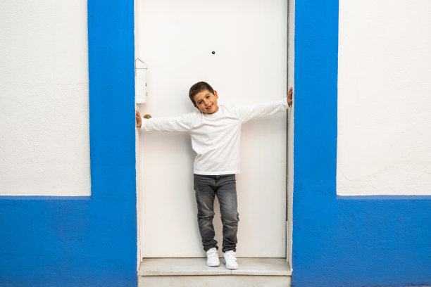 一个小孩站在一扇蓝白相间的门前图片下载