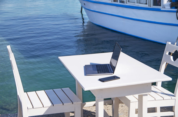 在蓝色海边的热带海滩办公室里用笔记本电脑和电话在线工作图片下载