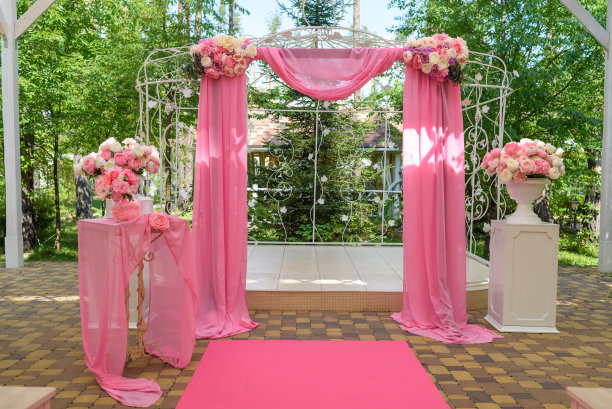 粉红色的婚礼场地，户外用鲜花和粉红色的布装饰婚礼拱门。美丽的婚礼装饰，自由的空间图片下载