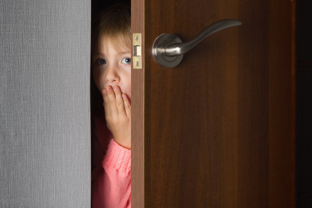 一个孩子，一个小女孩，从半掩着的房门向外张望。幼稚的好奇心。图片下载
