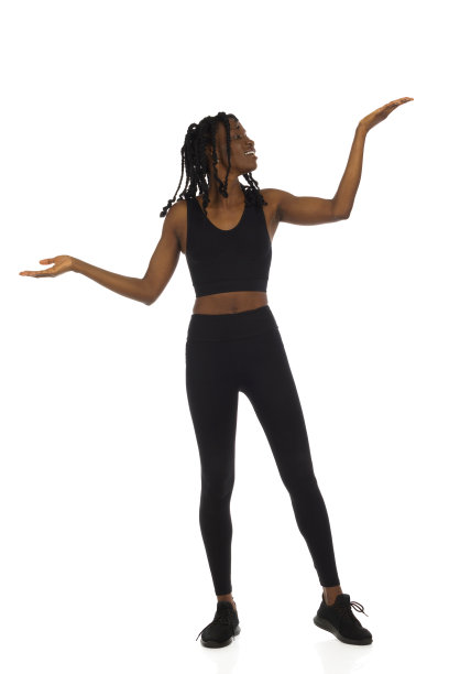 快乐的黑人妇女穿着运动服，举起双手站在那里比较着什么。完整的孤立。图片下载