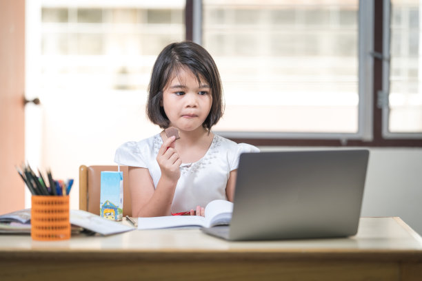 亚洲女学生在家里通过笔记本电脑上网学习时在笔记本上写作。教育概念专题图片图片下载
