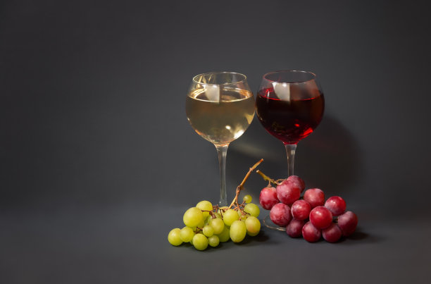 杯中有红葡萄酒和白葡萄酒，灰色背景下有葡萄树枝。图片下载
