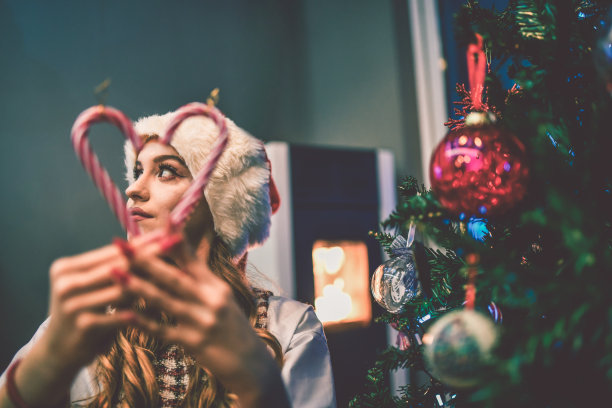 可爱的女青少年玩糖果拐杖，庆祝圣诞节在树下图片下载