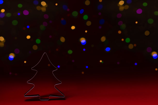 圣诞树形状的饼干切割器在红色背景上与散景，低调，复制空间图片下载