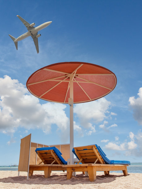 沙滩上有遮阳伞和日光浴床，映衬着蓝天。图片下载