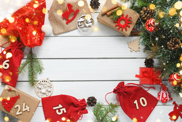 圣诞快乐。出现日历。圣诞礼物和惊喜放在白色的木桌上，旁边是圣诞树的树枝和闪闪发光的灯。贺卡或网站横幅。DIY。图片下载