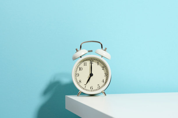 桌子上的白色圆形闹钟。早上七点，早起，换小时图片下载