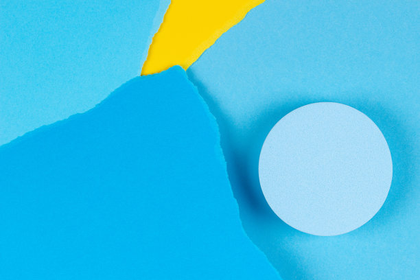 俯视图为几何圆形讲台产品展示，黄色和蓝色撕碎的纸片在浅蓝色的纸背景上图片下载