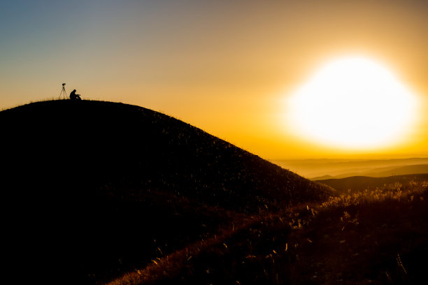 摄影师在日落时在山上阅读和放松图片下载