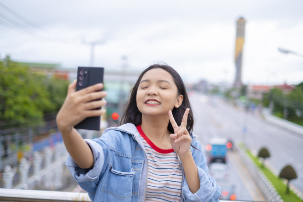肖像微笑小女孩在道路背景上使用手机。图片下载
