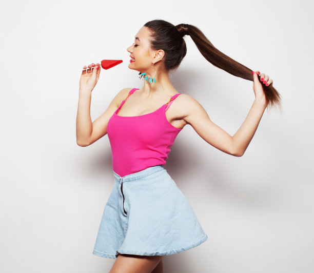 漂亮的年轻女子，手里拿着棒棒糖，白色背景图片下载