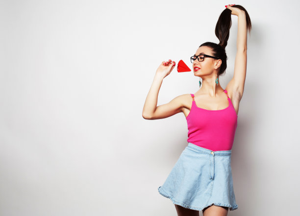 年轻的黑发女人手里拿着棒棒糖在白色背景上图片下载